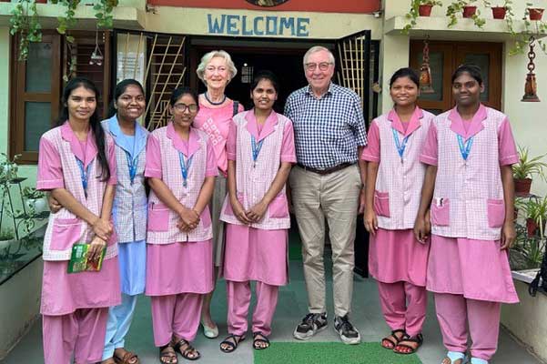 Eine Gruppe von jungen indischen Frauen steht in Krankenschwesterkleidung vor einem Krankenhaus